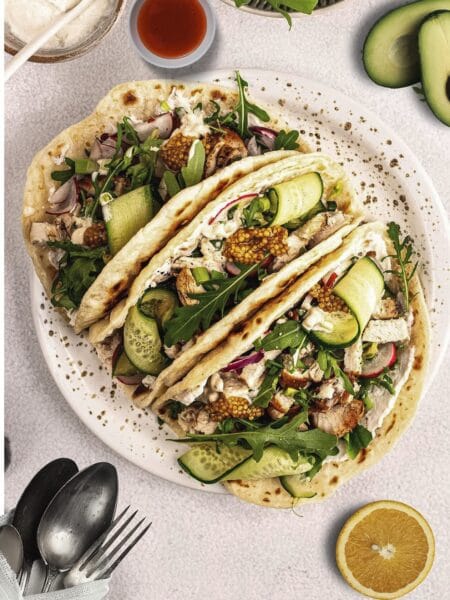 Chicken tacos with avocado salsa served on a plate with lime wedges and fresh cilantro