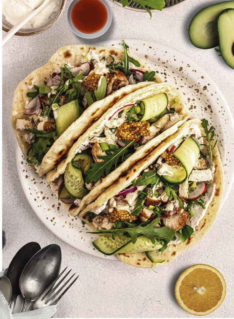 Chicken tacos with avocado salsa served on a plate with lime wedges and fresh cilantro