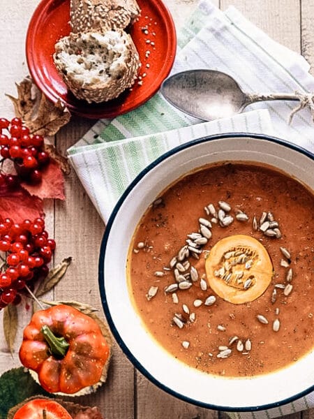 Roasted butternut squash soup with apple served in a bowl topped with fresh herbs